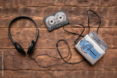 Portable retro stereo cassette player, old headphones and cassettes ont he brown wooden table background.