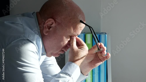 Tired Businessman Takes Out His Eyeglasses and Rubs His Eyes with His Hand photo