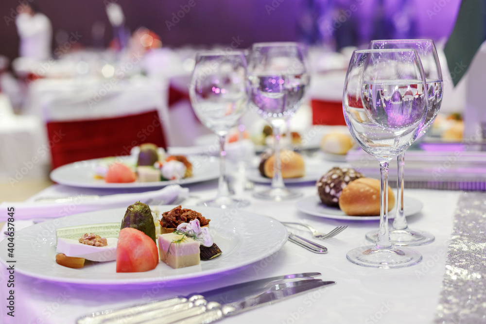 Festive round table setting in a prestigious restaurant for dinner. Banquet decoration with white and red