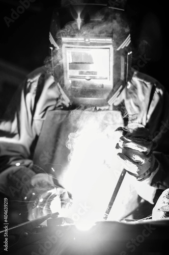Elderly man welding in a workshop surrounded by tools