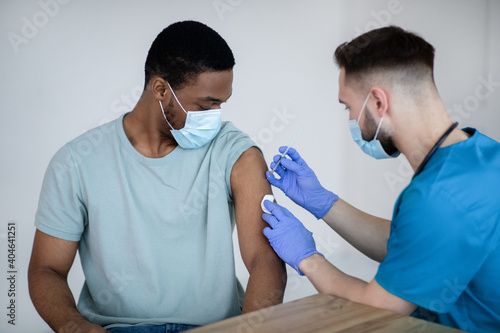 African American male patient getting immunized against covid-19, receiving antiviral vaccine injection at health centre photo