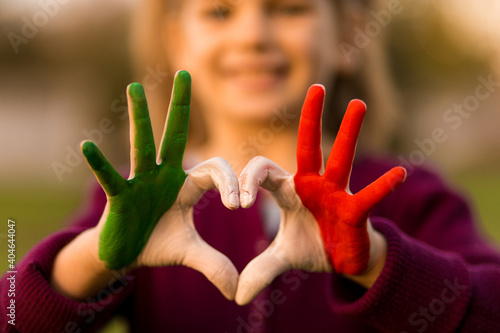 Heart shape of kids hand painted in italy flag colors, kids body language, childrens love concept. Heart hand on nature sunset bokeh background