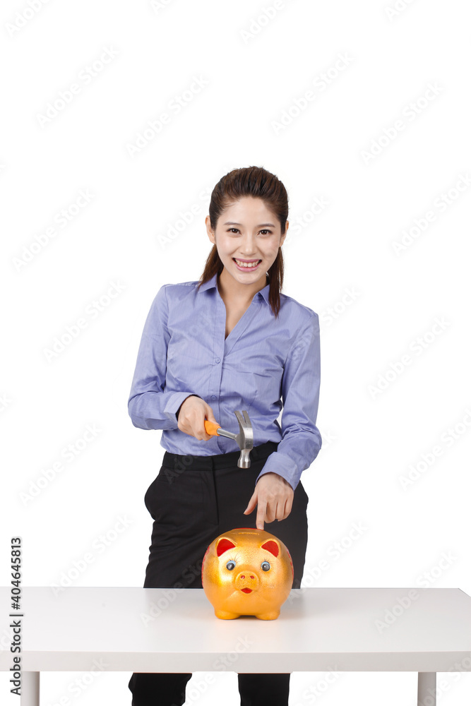 Businesswoman using hammer to smash open a piggybank Businesswoman using hammer to smash open a piggybank