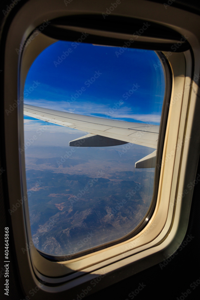 View from the porthole window flying airplane on the airplane wing. Flying and traveling concept