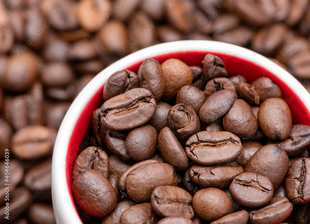 Naklejka premium Fresh coffee beans in the mug with coffee beans background.