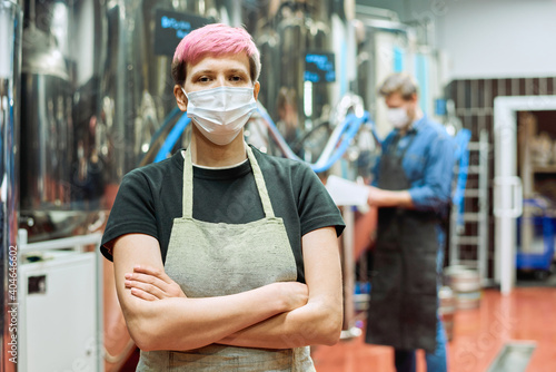 Young female brewer in apron and protective mask crossing arms by chest © pressmaster