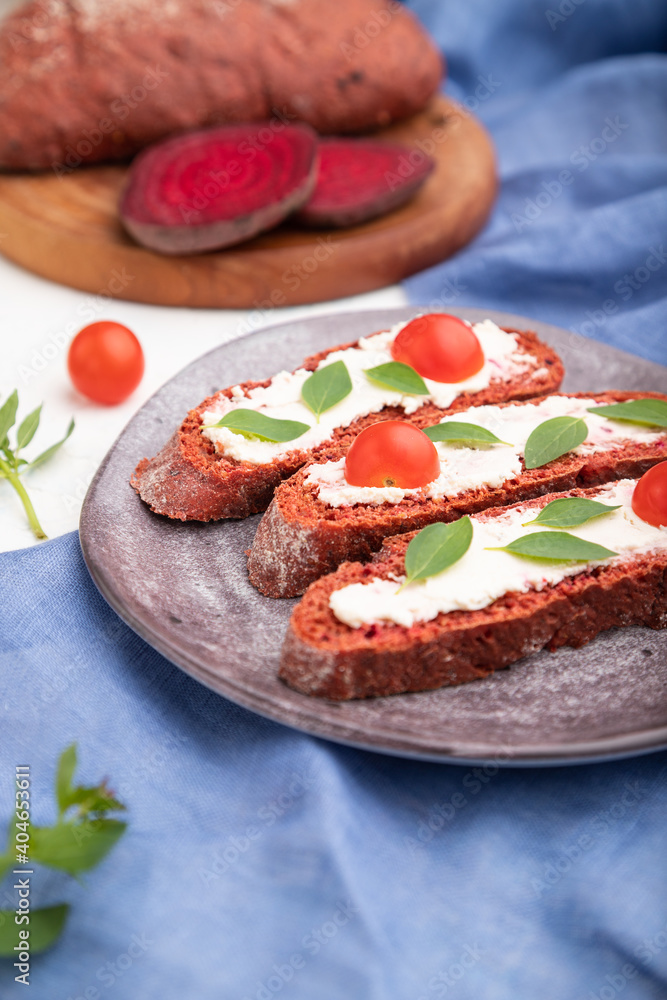 Red beet bread sandwiches with cream cheese and tomatoes on white concrete background. Side view, selective focus.