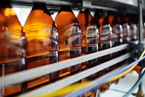 Industrial production of plastic bottles for low-alcohol beverages, soda and sunflower oil. Empty PET bottles of brown color on the background of modern equipment.