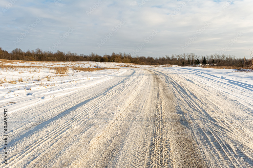 The winding snow-covered road goes into the horizon. Sunny winter day with blue skies and small clouds The winding snow-covered road goes into the horizon. Sunny winter day with blue skies and small clouds