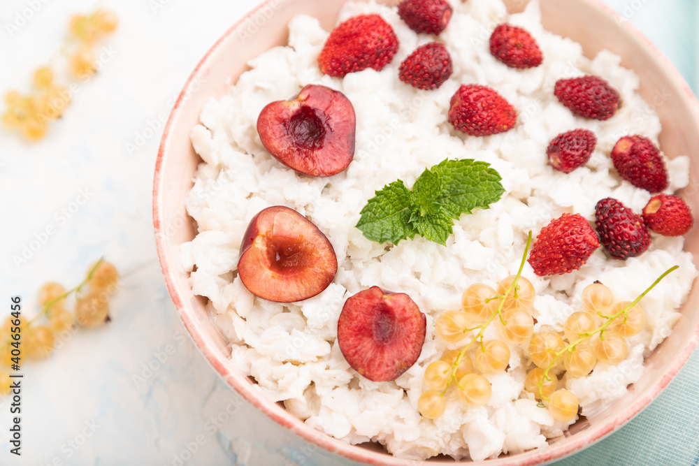 Rice flakes porridge with milk and strawberry in ceramic bowl on white concrete background. Top view, close up. Rice flakes porridge with milk and strawberry in ceramic bowl on white concrete background. Top view, close up.