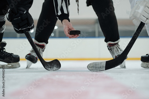 Canvastavla Hand of referee holding puck over ice rink with two players standing around him