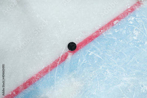 Puck lying on red line dividing play space and zone of net on large ice rink