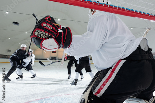 Quadro em tela Back view of hockey player in sports uniform and gloves standing in the net