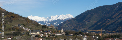 Picturesque mountain landscape in Naturns in South Tyrol in autumn, in the fore an old church, castle and old buildings and in the background the snow-covered Alps, no people