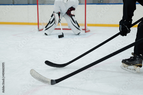 Photography Hockey sticks held by two players in sports uniform on background of goal keeper