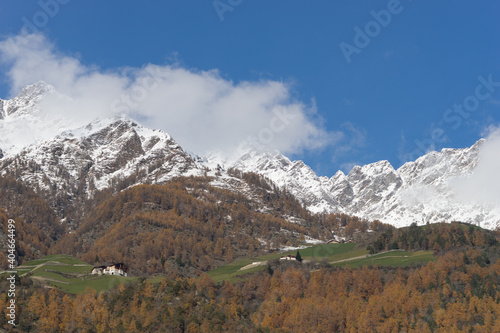 Picturesque mountain landscape in Naturns in South Tyrol in autumn, in the background the snow-covered mountains, blue sky with clouds, no people