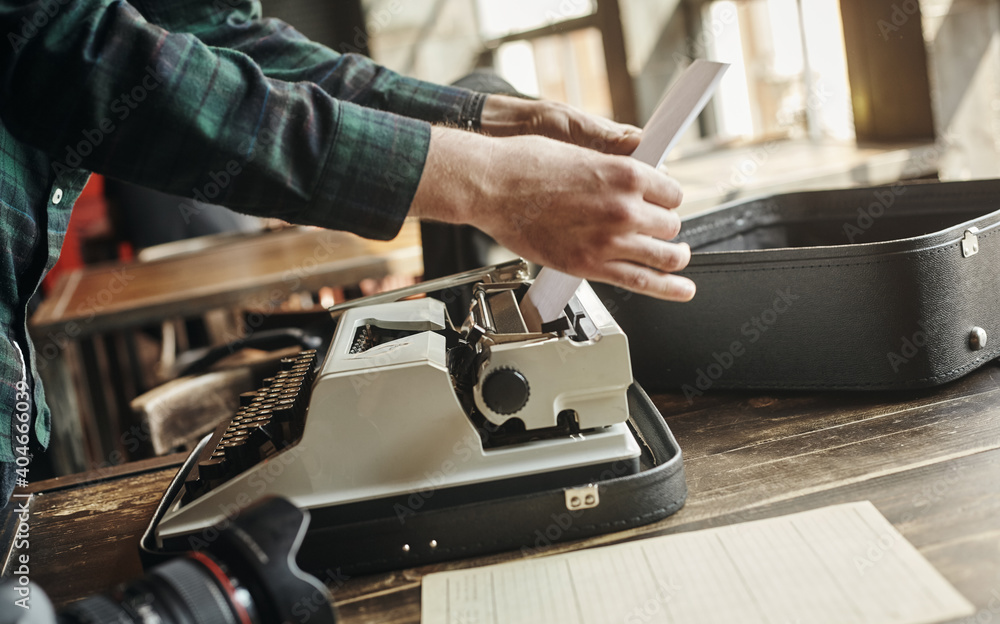 a business man hand pulling a sheet of paper from an old grungy manual portable typewriter a business man hand pulling a sheet of paper from an old grungy manual portable typewriter