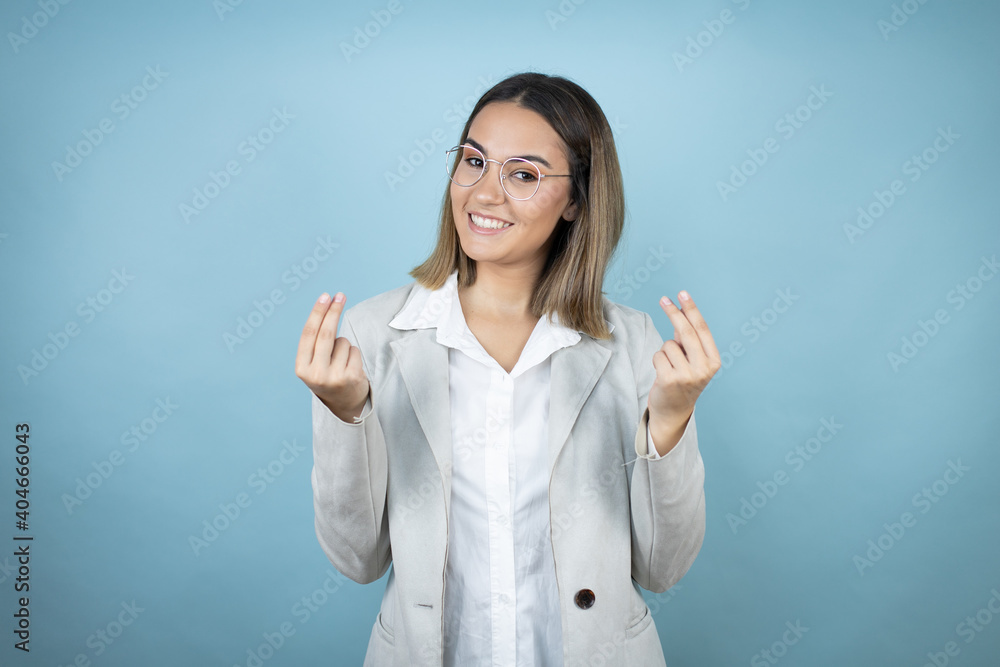 Young business woman over isolated blue background doing money gesture with hands, asking for salary payment, millionaire business Young business woman over isolated blue background doing money gesture with hands, asking for salary payment, millionaire business