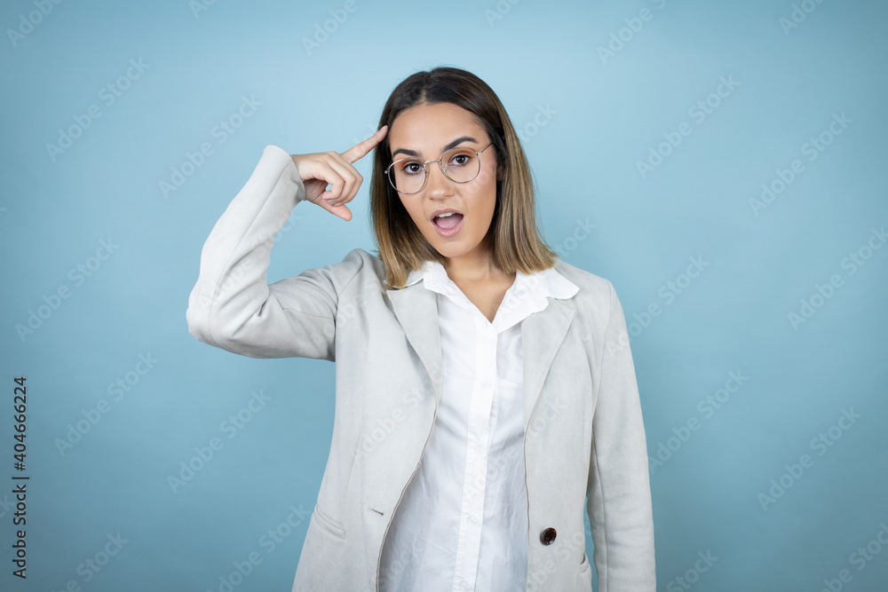 Young business woman over isolated blue background smiling and thinking with her fingers on her head that she has an idea. Young business woman over isolated blue background smiling and thinking with her fingers on her head that she has an idea.
