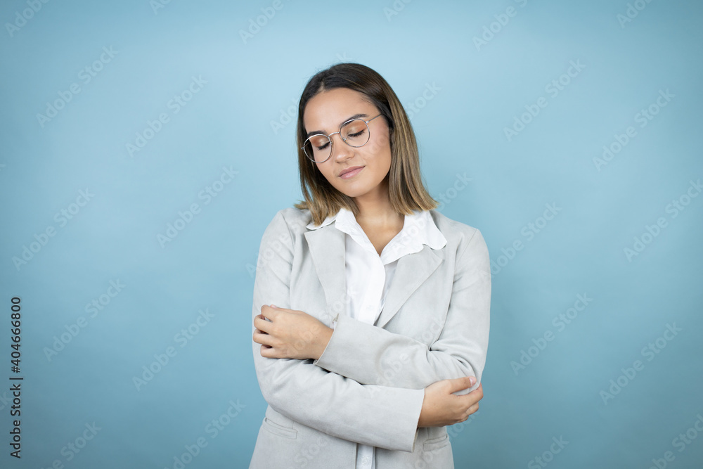 Young business woman over isolated blue background hugging oneself happy and positive, smiling confident Young business woman over isolated blue background hugging oneself happy and positive, smiling confident