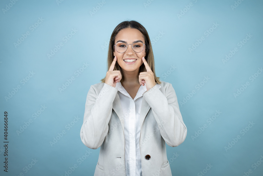 Young business woman over isolated blue background smiling confident showing and pointing with fingers teeth and mouth Young business woman over isolated blue background smiling confident showing and pointing with fingers teeth and mouth