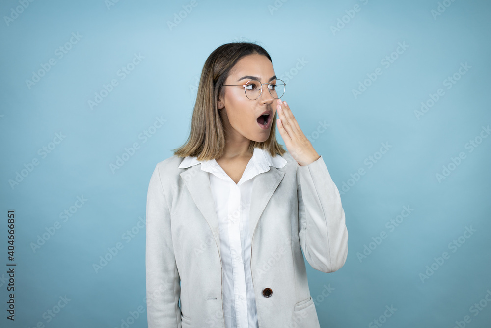 Young business woman over isolated blue background covering mouth with hand, shocked and afraid for mistake. surprised expression Young business woman over isolated blue background covering mouth with hand, shocked and afraid for mistake. surprised expression