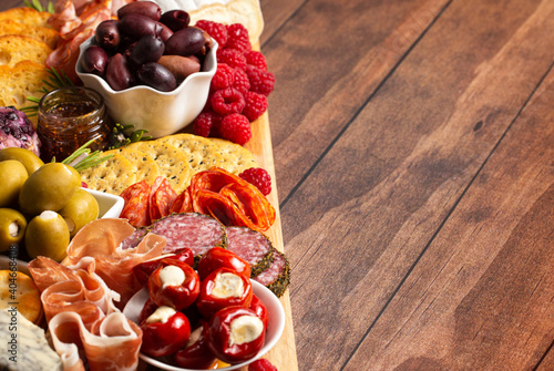 A Savoury Charcuterie Board Covered in Meats Olives Peppers Berries and Cheese photo