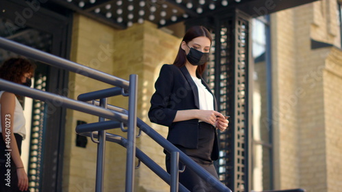 Mask woman meeting with masked courier outdoors. Businesswoman paying card order