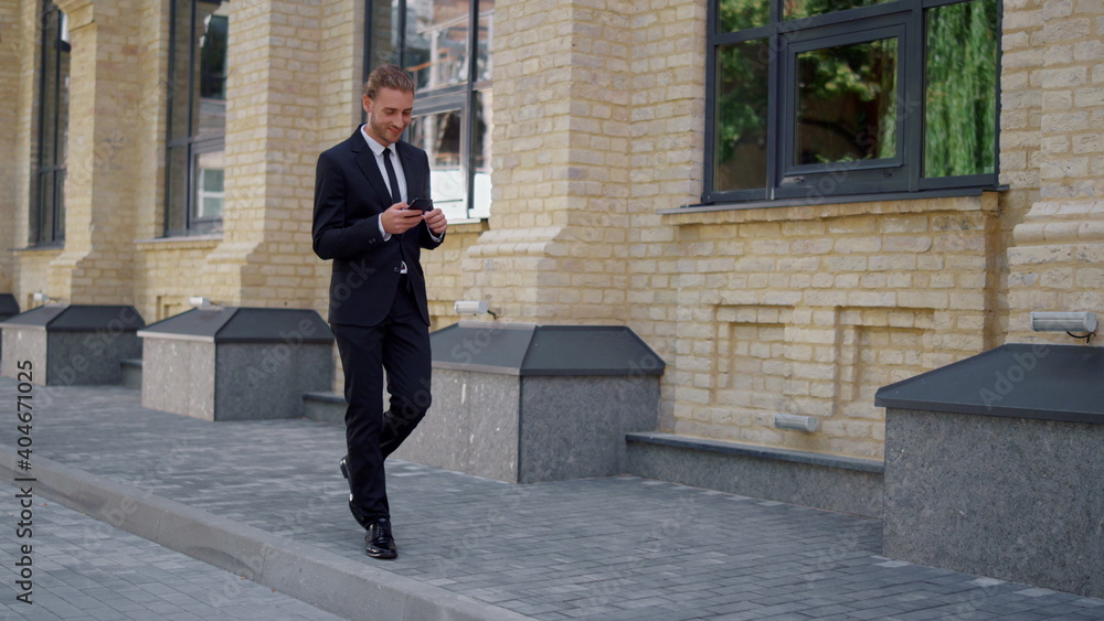 Businessman using mobile phone on street. Man looking cellphone screen outdoors.