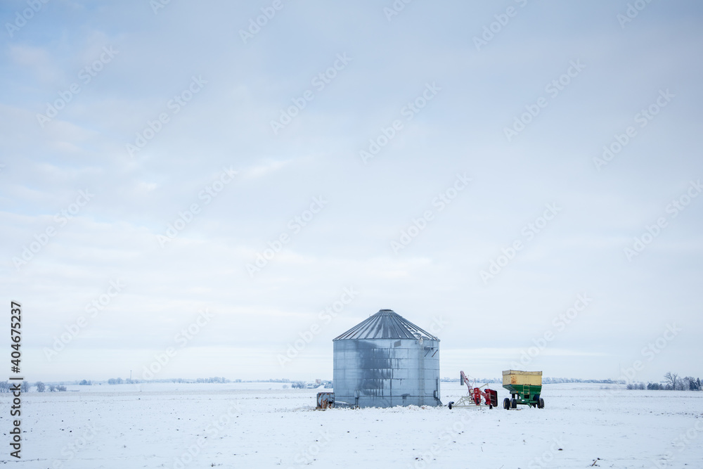 grain silo on winter field with farm tractors