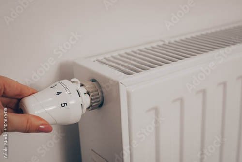 A woman's hand turns the battery heating knob. Heating in an apartment, at home. Heating prices.