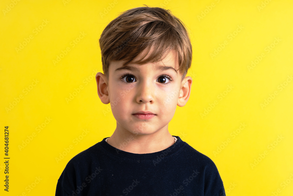 Front view portrait of small caucasian boy in front of yellow wall Front view portrait of small caucasian boy in front of yellow wall