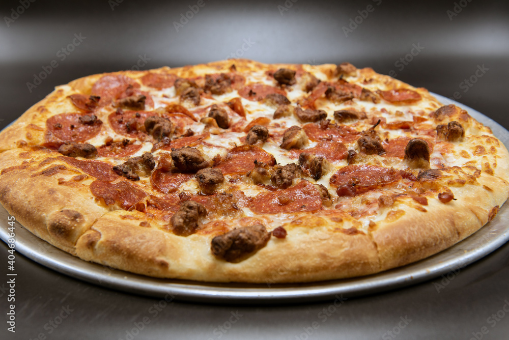 Pepperoni and sausage dominate the top of the melted cheese pizza of meat.