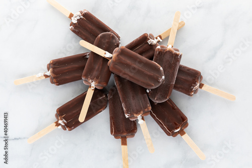 Top down view of a pile of chocolate covered ice cream popsicles against a light background. photo