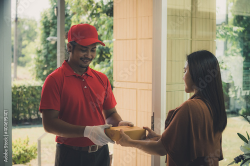 The safe delivery concept, A courier in a red uniform take the parcel to the customer home.