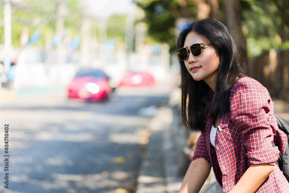 Asian woman in sunglasses is sitting on a street in urban.