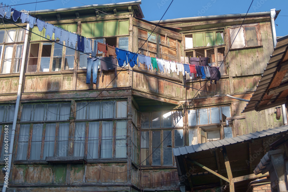 The laundry is dried in the yard on ropes behind wooden house facade