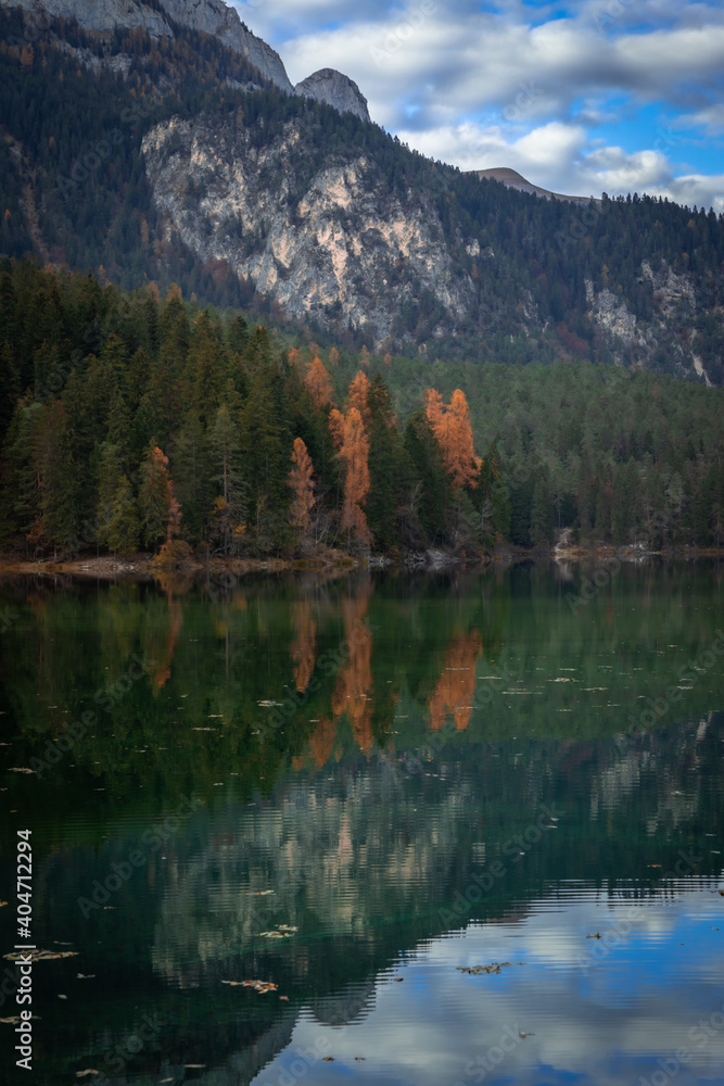 Esmerald lake and mountains in autumn with a cloudy sky and yellow trees