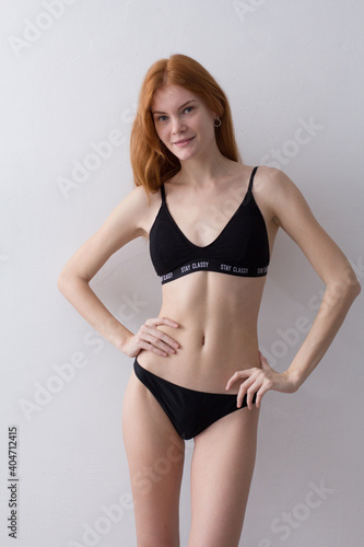 snap shot of pretty model in black lingerie on white background with red hair	