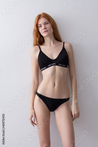 snap shot of pretty model in black lingerie on white background with red hair  © Zaliya