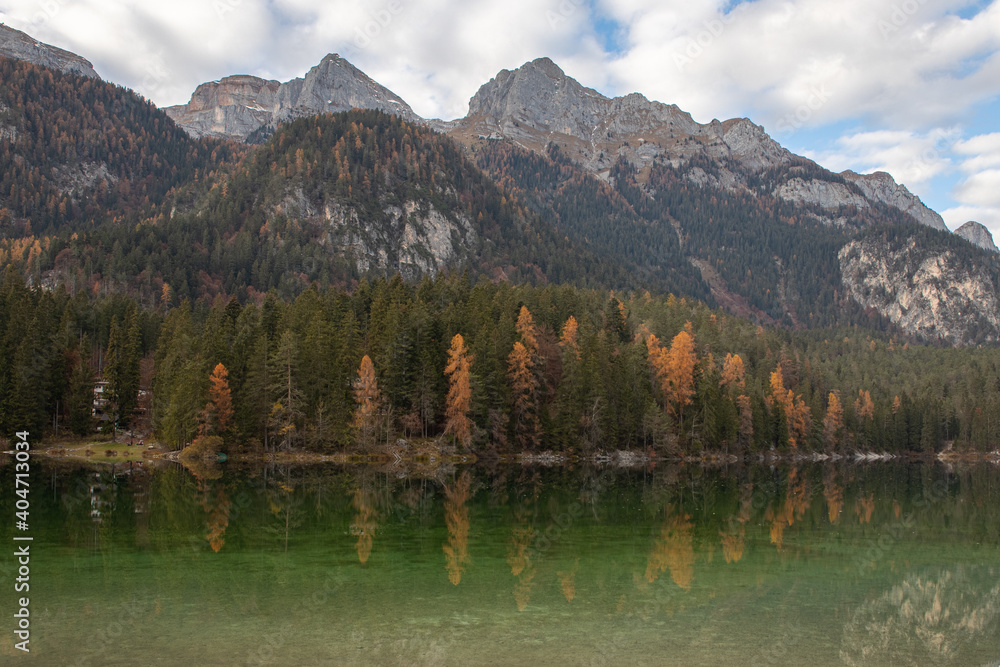 Esmerald lake and mountains in autumn with a cloudy sky and yellow trees