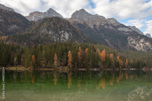 Esmerald lake and mountains in autumn with a cloudy sky and yellow trees