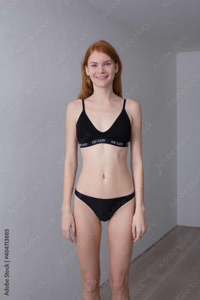 Fototapeta premium snap shot of pretty model in black lingerie on white background with red hair 