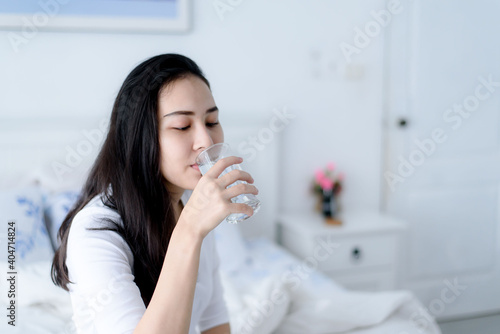 Young woman drink water in a bedroom.