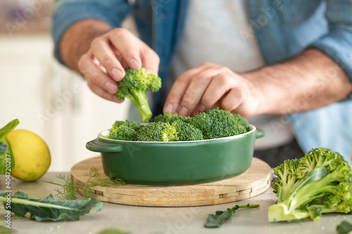 Male hands preparing diet healthy food of baked broccoli at home kitche
