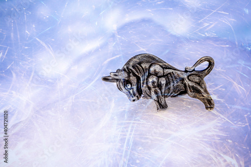 Bull symbol of the year 2021. Year of the white metal bull according to the Chinese calendar. Souvenir bull made of silver metal on a snow background with bokeh effect. High quality photo