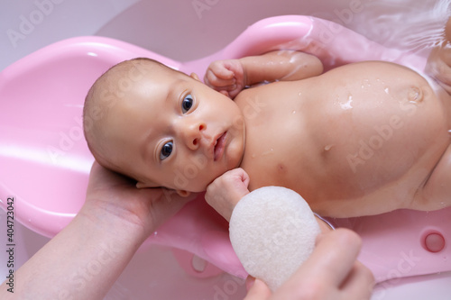 a newborn is washed with a sponge in the bathroom