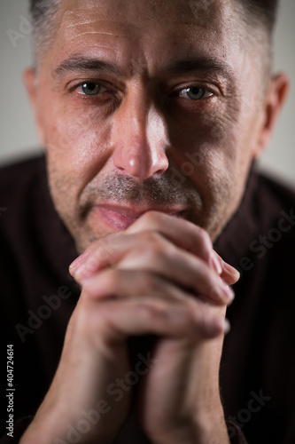 portrait of an adult man, hands folded together, looking at the camera.