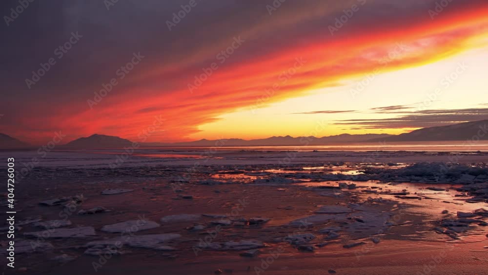 Colorful bright sunset over Utah Lake frozen in winter panning the broken ice on the surface of the water. Colorful bright sunset over Utah Lake frozen in winter panning the broken ice on the surface of the water.
