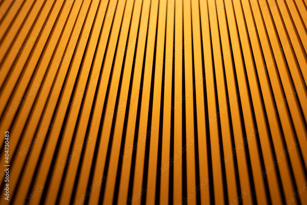 Abstract background of wooden battens illuminated by warm light. Repetitive non-parallel lines. Background from wooden sticks. Lamp in the interior. Shooting the details of the lighting fixture. Abstract background of wooden battens illuminated by warm light. Repetitive non-parallel lines. Background from wooden sticks. Lamp in the interior. Shooting the details of the lighting fixture.